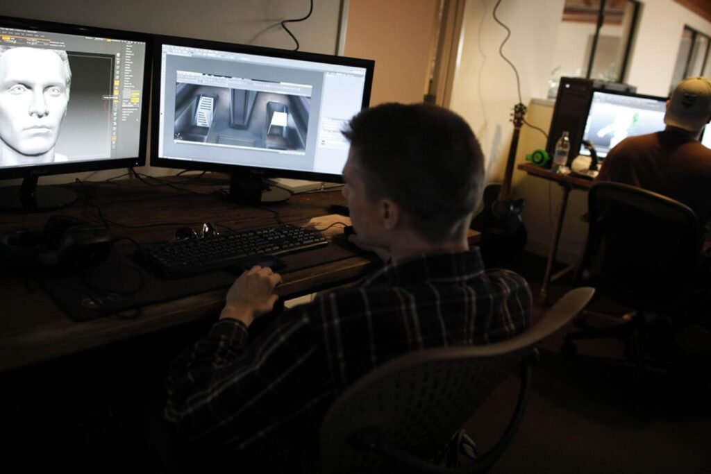 Un artiste travaille sur plusieurs écrans affichant un cockpit en 3D